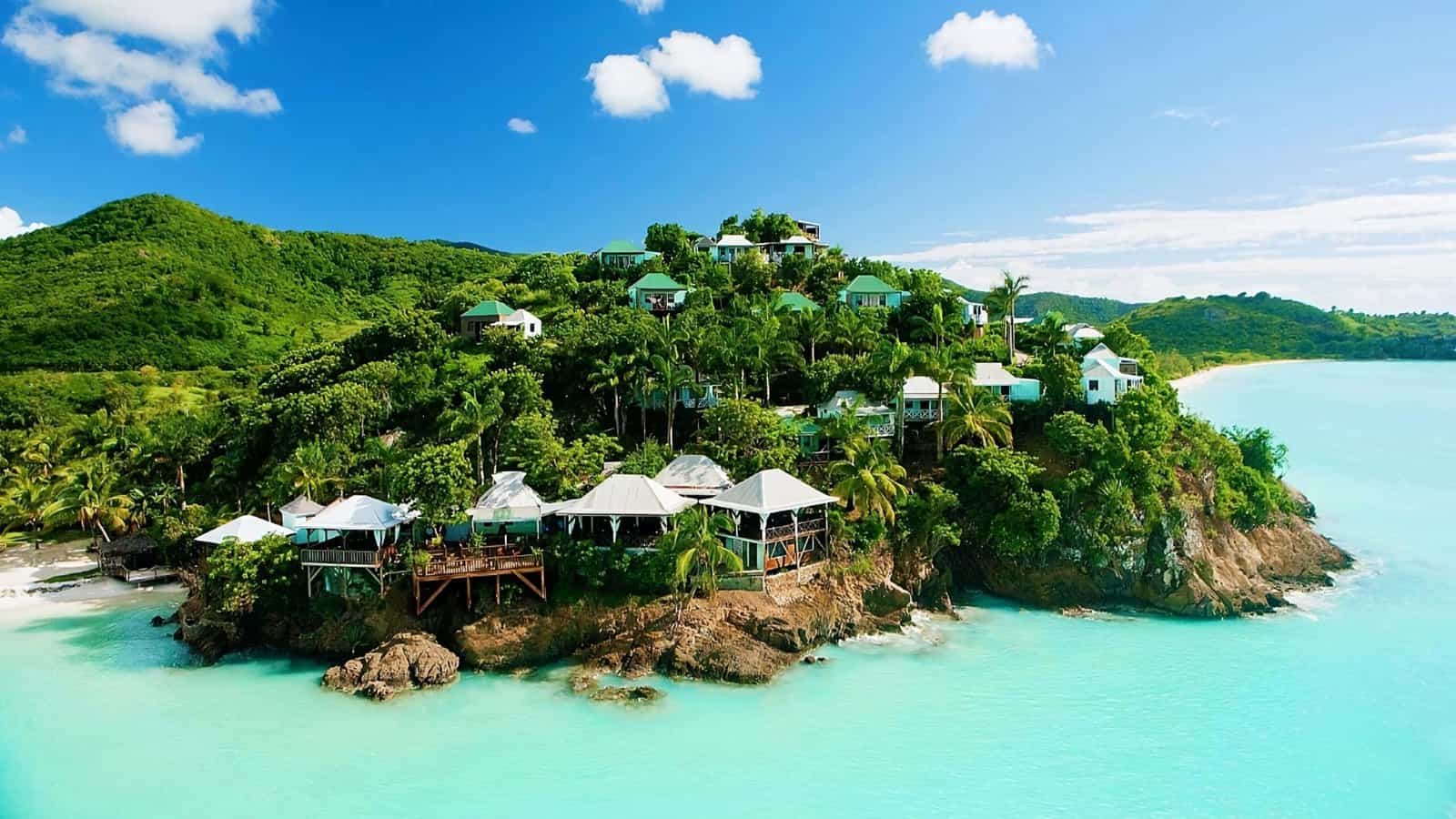 aNTIGUA BLUE WATER looking at a small island neck hillside with multiple homes up off the water in the lush greens affordable caribbean island visit