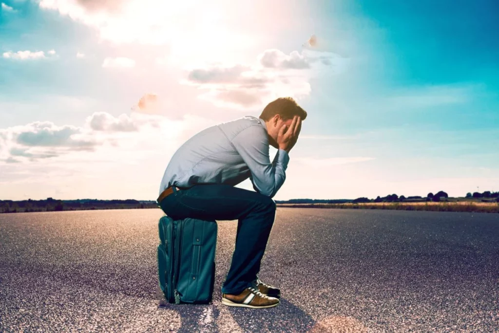 Man sitting on luggage in middle of road
