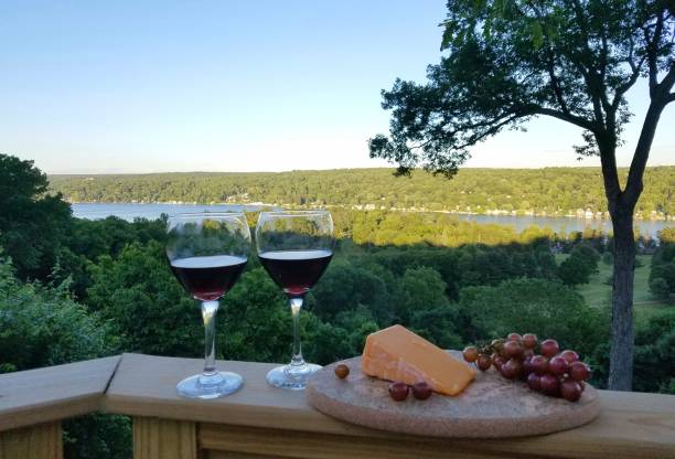 Two wine glasses filled with a Cabernet style wine with a platter of cheese and red grapes against a water background; travel and wine tasting ideas, Finger Lakes, wine tours. finger lakes winery stuben NY Watkins Glen Wine Cheese Grapes overlooking the lake