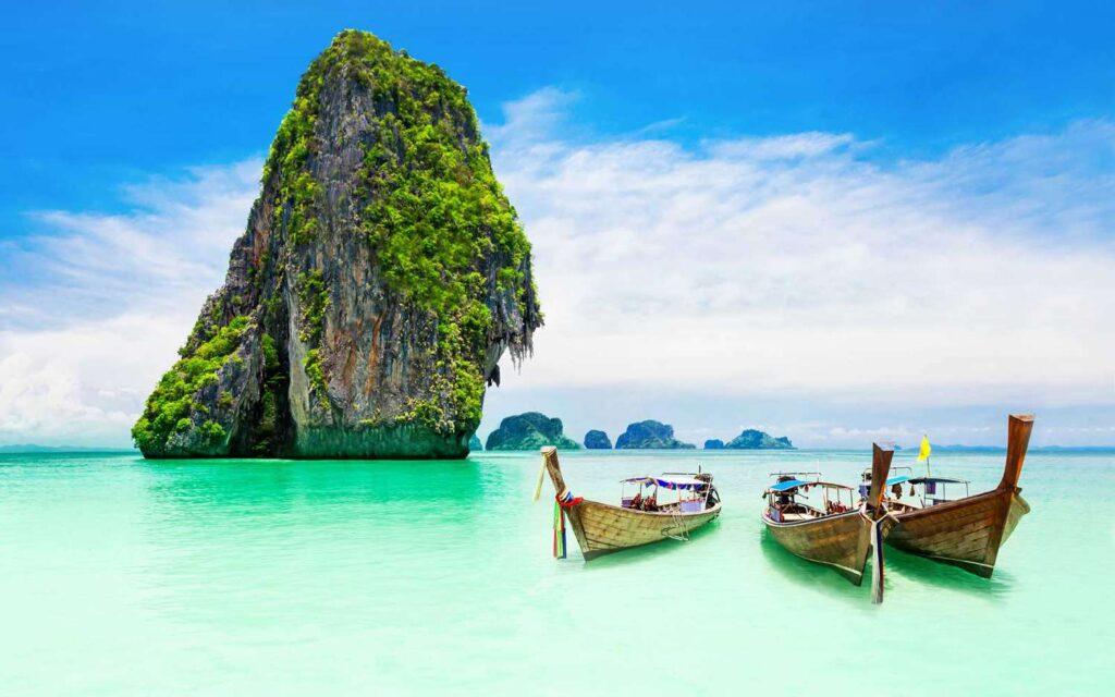 Stunning look from the beach looking out to a large singular stone island covered in green growth with aqua green calm water Luxury Travel Destinations