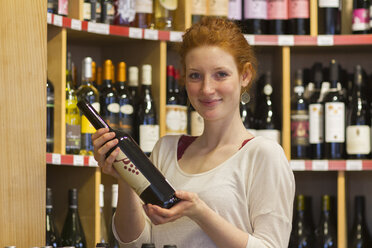 Red headed woman holding bottle of wine save money on food while traveling