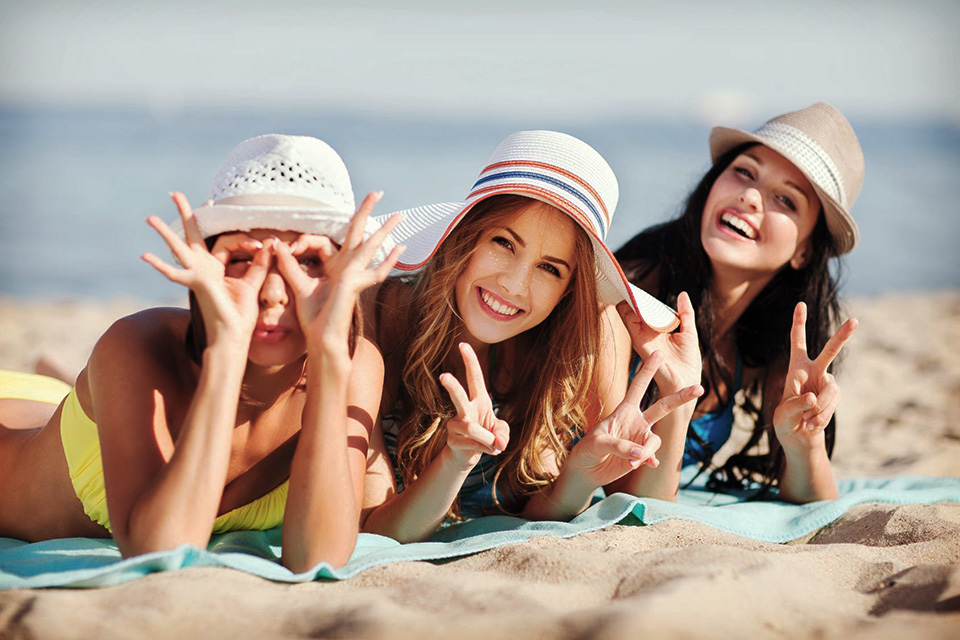 miami beach weekend trip picture of girls laying on beach waving at camera on exciting weekend getaway