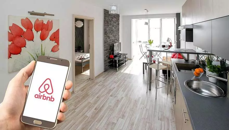 room of airbnb with a cellphone in forground with airbnb logo on phone